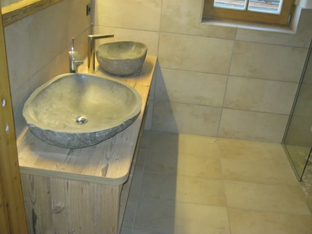 Badezimmer mit zwei Natursteinbecken auf einem Waschtisch aus Altholz