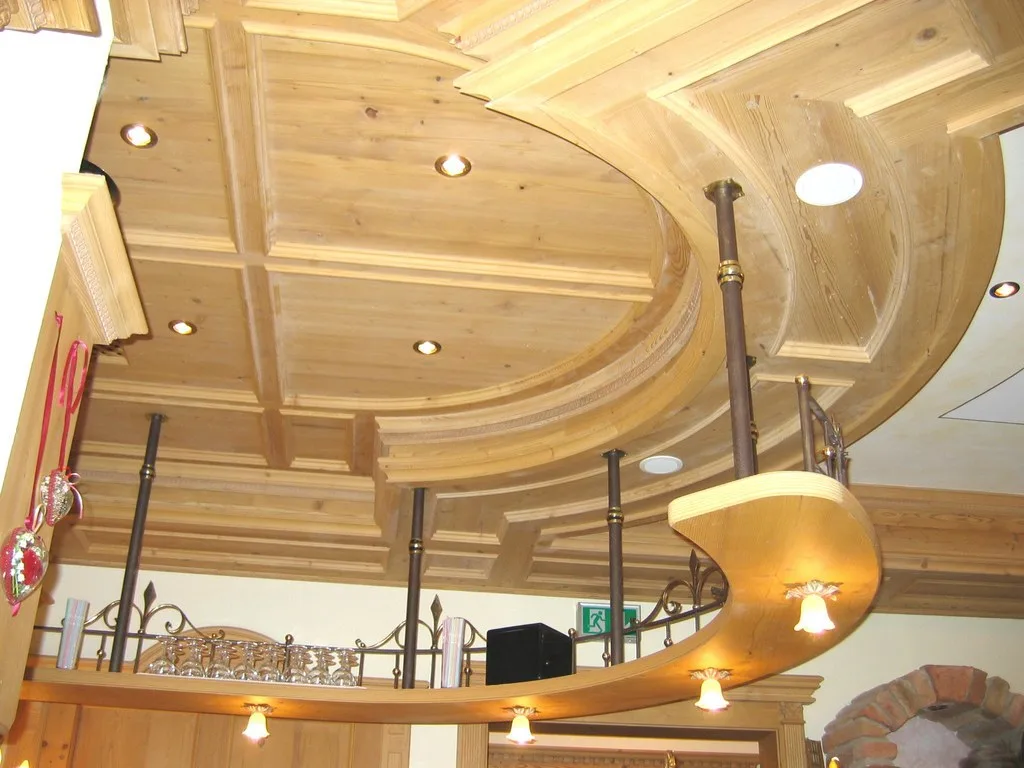 Kassettendecke aus Holz mit geschwungener, beleuchteter Galerie und Geländer in einem Hotel
