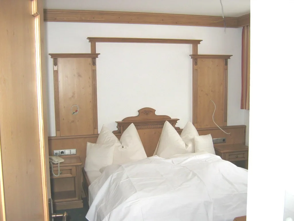 Hotelzimmer mit geschnitztem Kopfteil und Wandverkleidung aus Holz