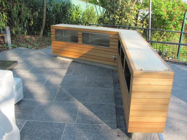 Bar in L-Form aus waagrechten Holzlatten auf einer Terrasse mit Steinplatten